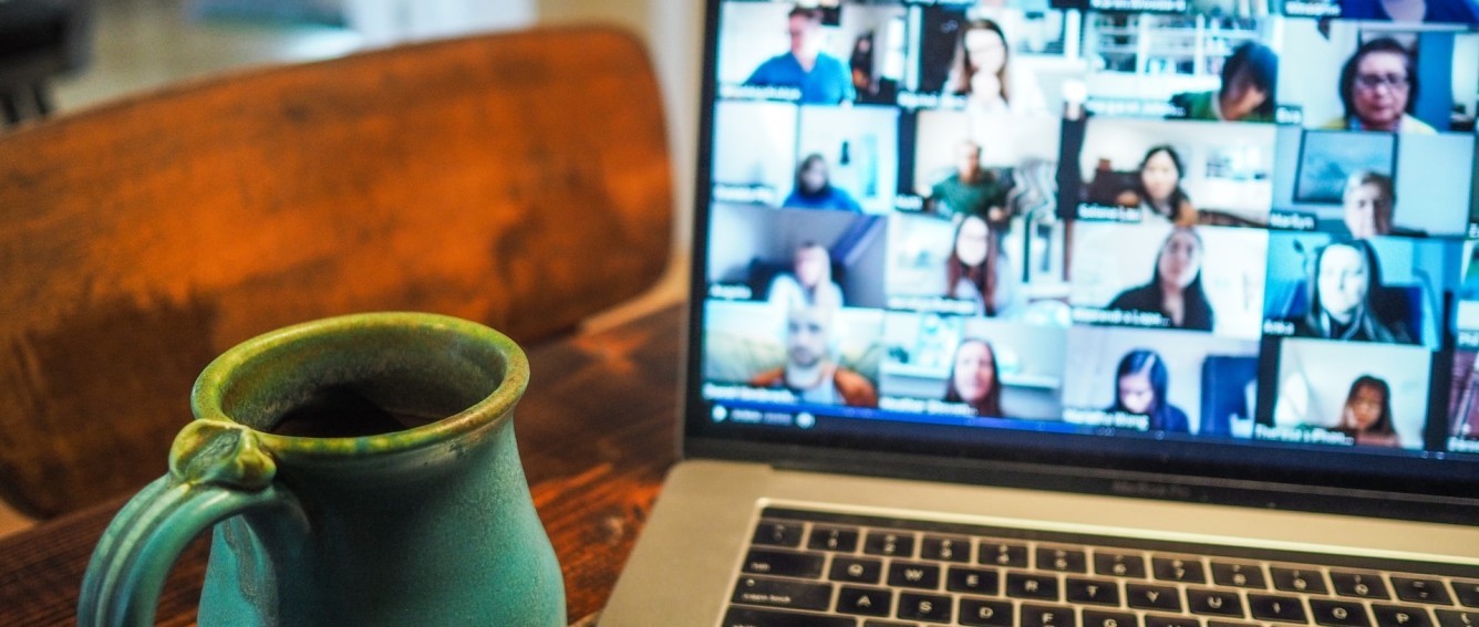 Zoom meeting on a laptop next to a mug