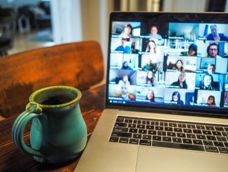 Zoom meeting on a laptop next to a mug